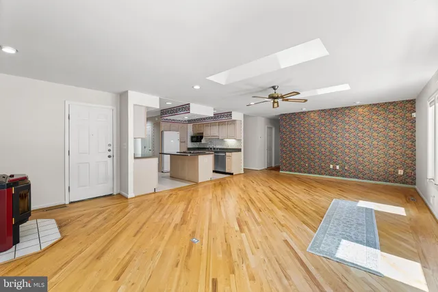 a view of empty room with wooden floor and kitchen