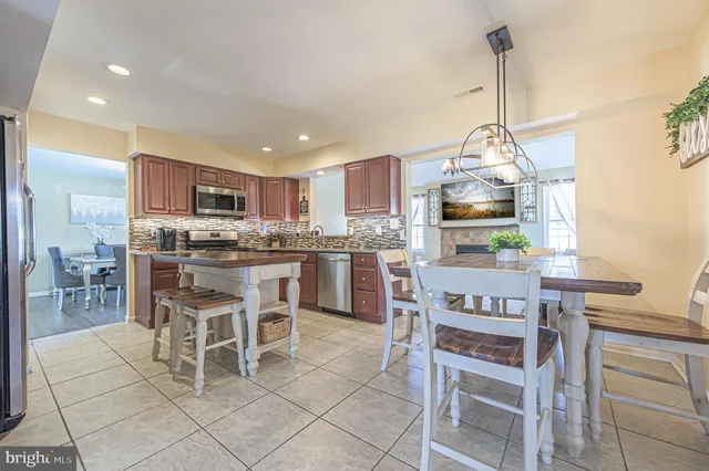 a kitchen with kitchen island granite countertop stainless steel appliances a sink a stove a table and chairs