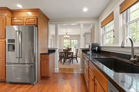 a kitchen with granite countertop a refrigerator a sink a stove and island with wooden floor