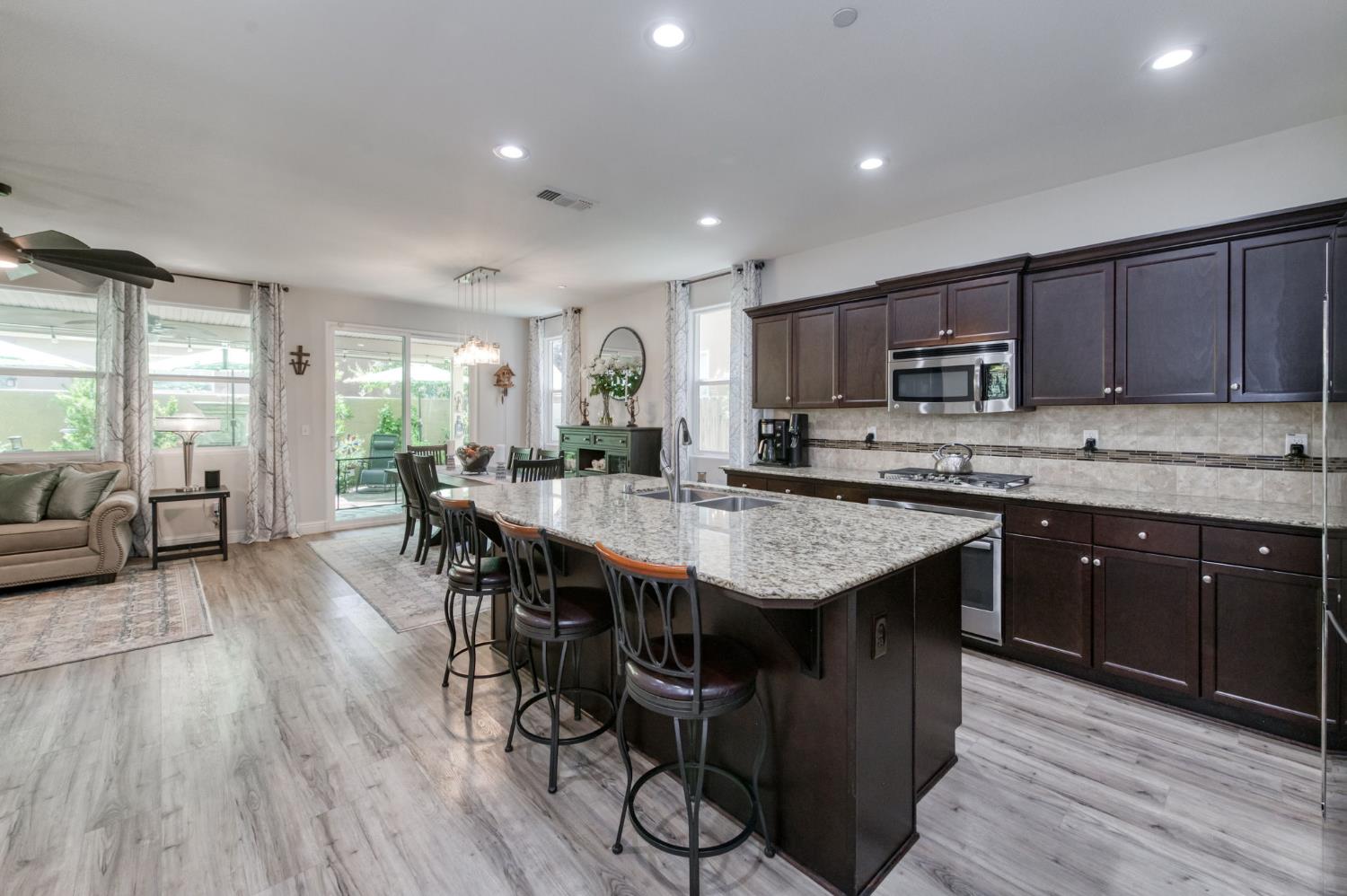 3562 Luminary Way Clovis, CA 93619 - Photo 5 of 40 a kitchen with kitchen island granite countertop wooden floors and wooden cabinets
