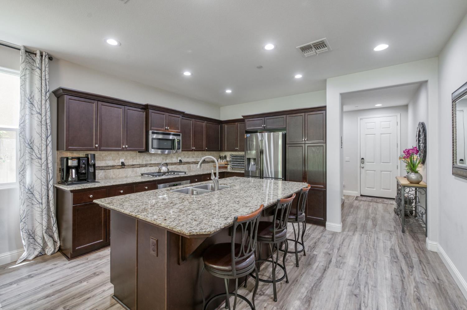 3562 Luminary Way Clovis, CA 93619 - Photo 6 of 40 a kitchen with stainless steel appliances granite countertop a kitchen island hardwood floor sink stove and refrigerator