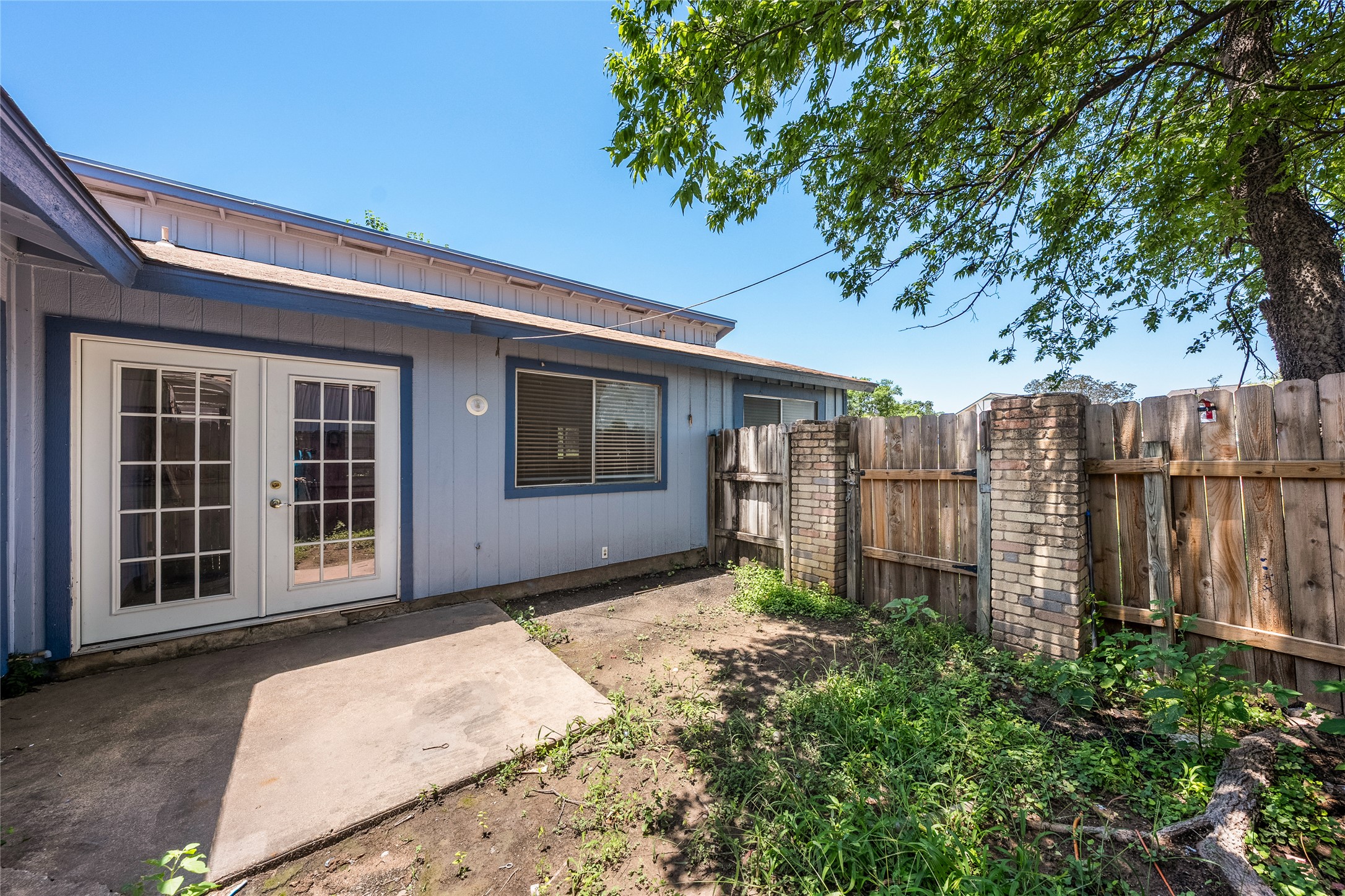 1111 West Rundberg Lane Austin, TX 78758 - Photo 13 of 16 A private backyard retreat featuring French doors and a sturdy wood fence with brick accents.
