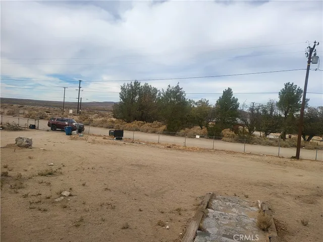 a view of a dry yard with wooden fence