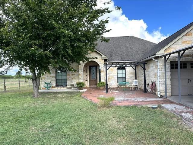 a front view of a house with a garden and trees