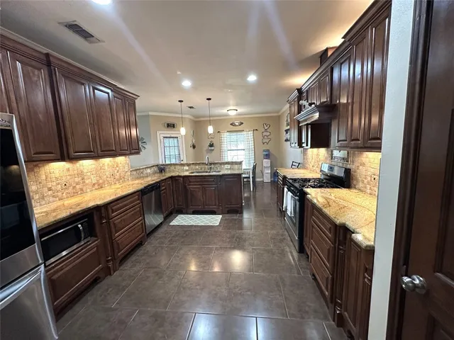 a large kitchen with stainless steel appliances wooden cabinets a stove and a sink