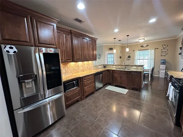 a large kitchen with stainless steel appliances granite countertop a refrigerator and a sink