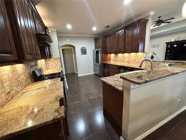 a kitchen with granite countertop stainless steel appliances a sink stove top oven and cabinets