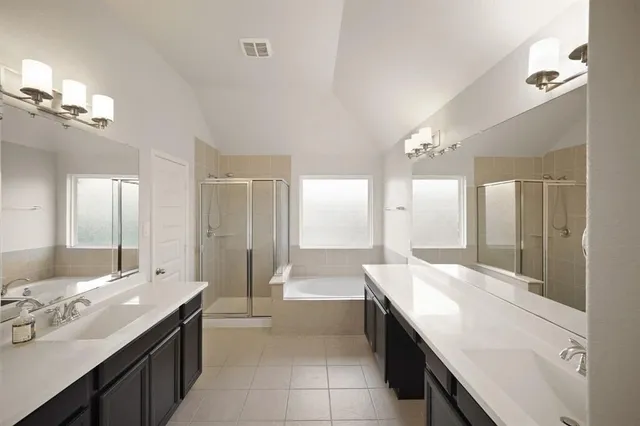 a large bathroom with a double vanity sink a large mirror and a bathtub