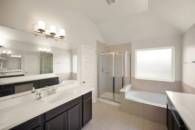 a bathroom with a tub a sink double vanity and a mirror