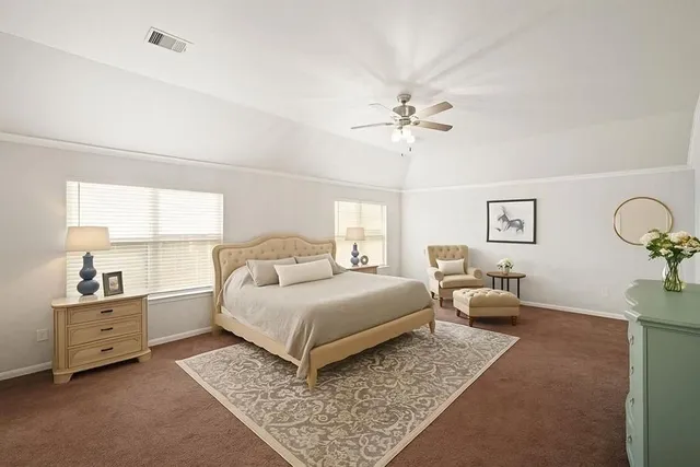 a spacious bedroom with a bed a dresser and a chandelier