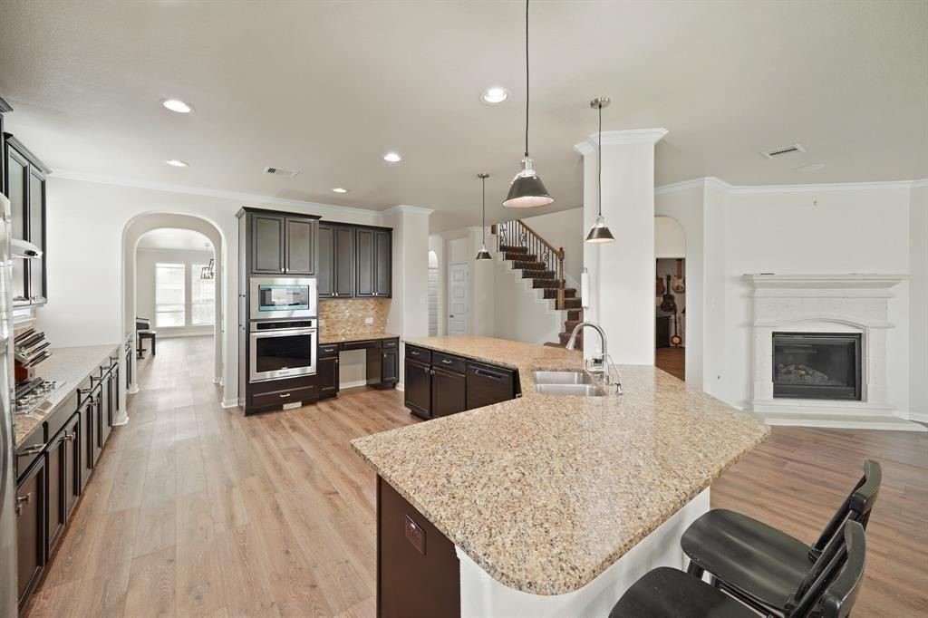 20358 Mathis Landing Drive Cypress, TX 77433 - Photo 5 of 32 a kitchen with stainless steel appliances kitchen island granite countertop a table chairs and a wooden floor