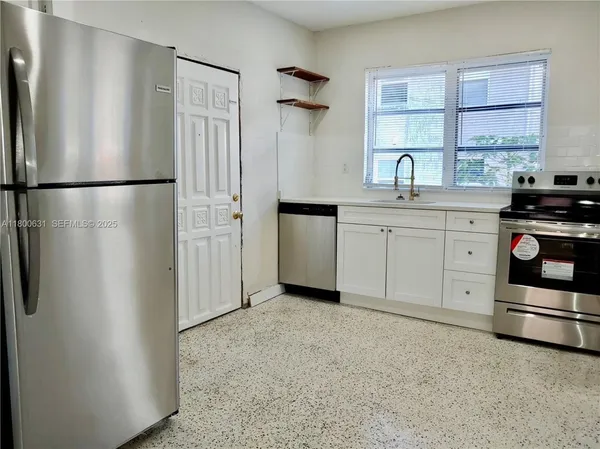 a kitchen with white cabinets and window