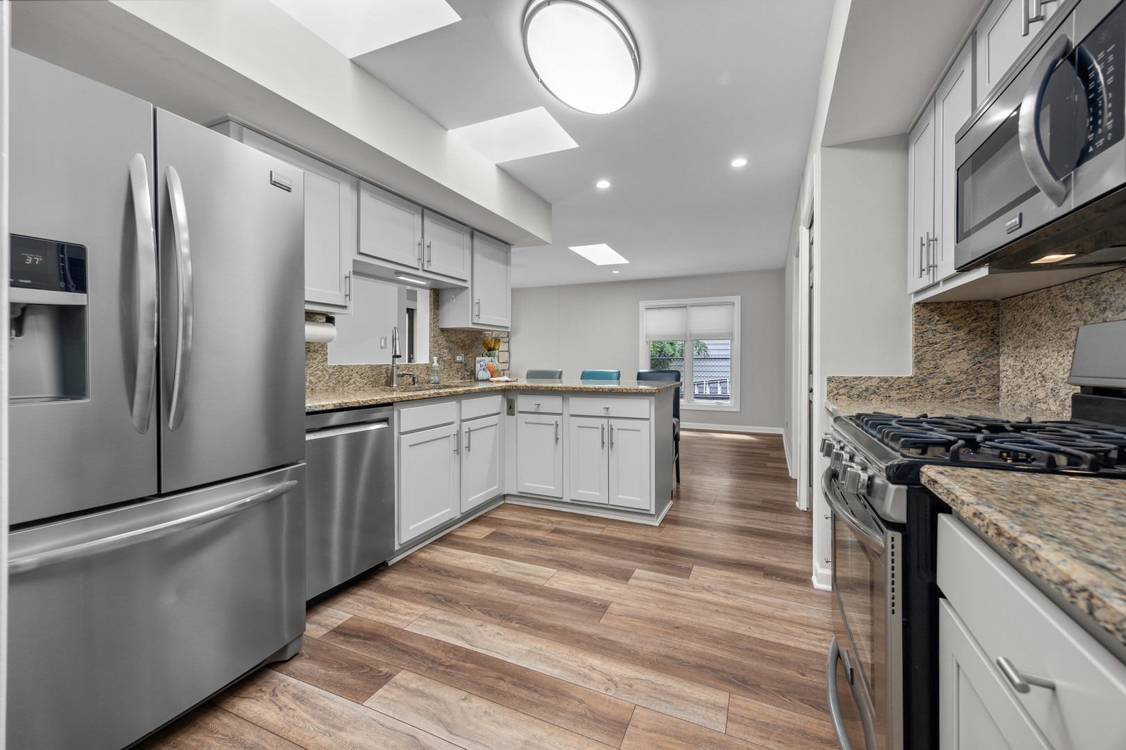 1505 Chartwell Road Hoffman Estates, IL 60169 - Photo 10 of 38 a kitchen with stainless steel appliances granite countertop a stove top oven a sink dishwasher a refrigerator and white cabinets with wooden floor