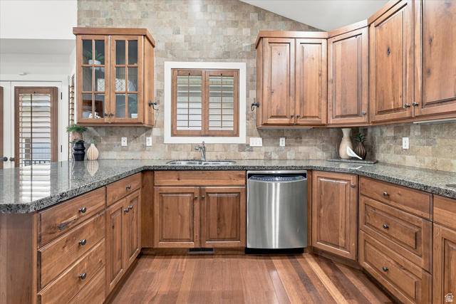 689 Apple Drive Logan, UT 84321 - Photo 13 of 52 Kitchen featuring wood-finish cabinetry, stone tile backsplash, wood-finish flooring, stainless steel dishwasher, and a double basin sink