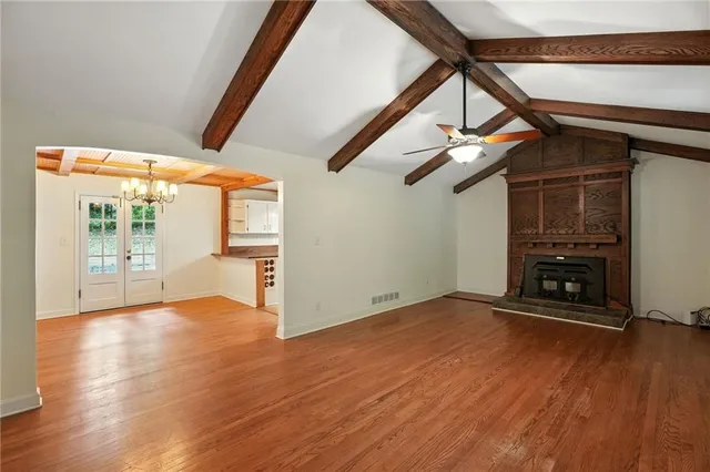 a view of an empty room with wooden floor and stairs