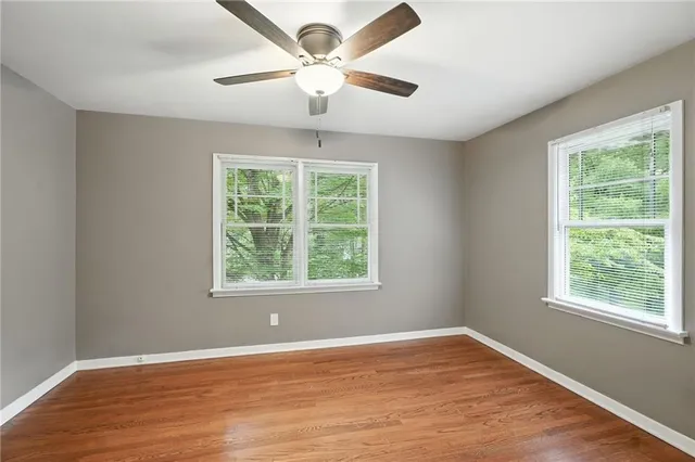 an empty room with wooden floor and a ceiling fan