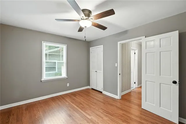 a view of an empty room with window and wooden floor