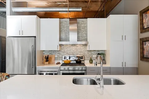 a kitchen with stainless steel appliances granite countertop a sink a refrigerator and a stove
