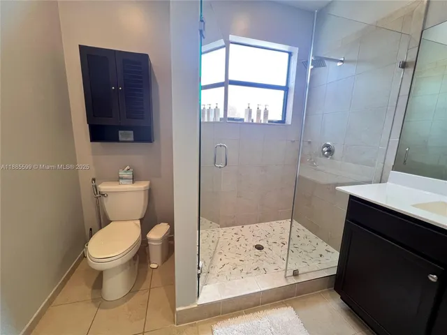 a bathroom with a toilet a sink a shower a mirror and a window