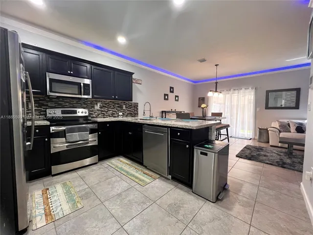 a kitchen with stainless steel appliances granite countertop a stove a sink and a refrigerator