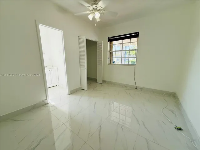 an empty room with chandelier fan and windows