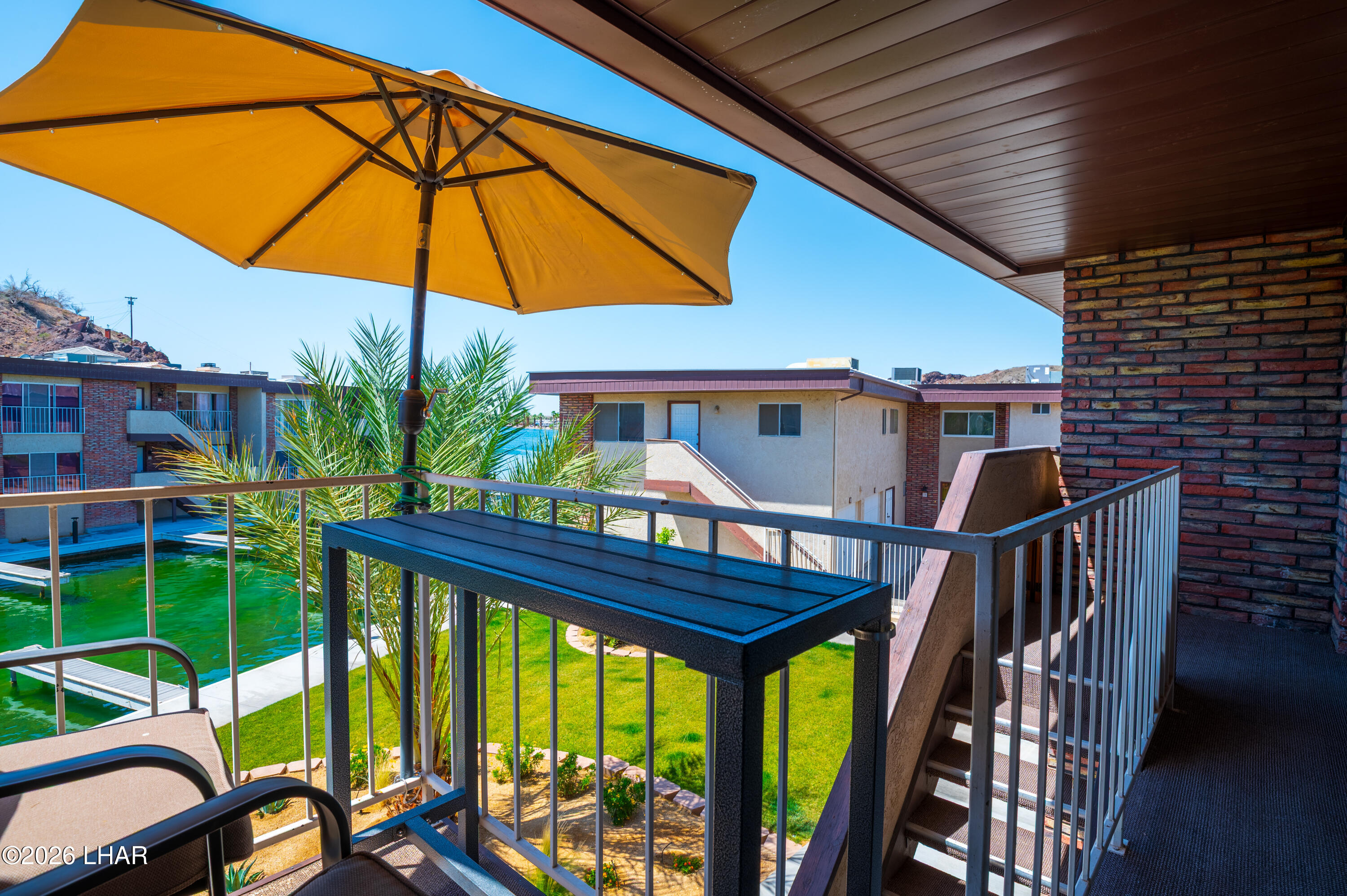 9170 Riverside Drive, Unit 13 Parker, AZ 85344 - Photo 7 of 51 a view of a patio with table and chairs under an umbrella with wooden floor