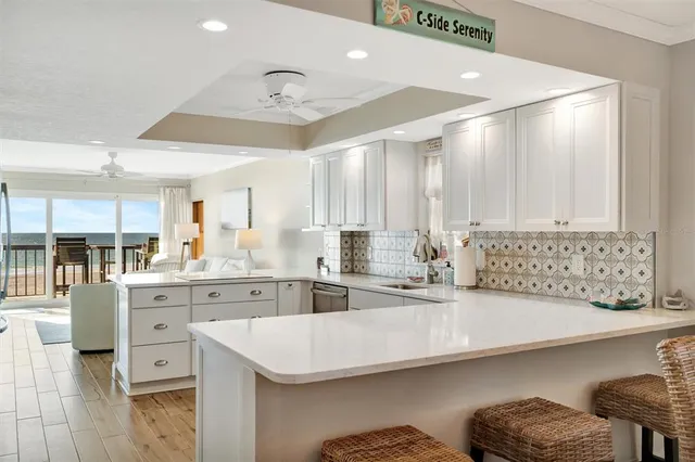 a kitchen with granite countertop a refrigerator and white cabinets