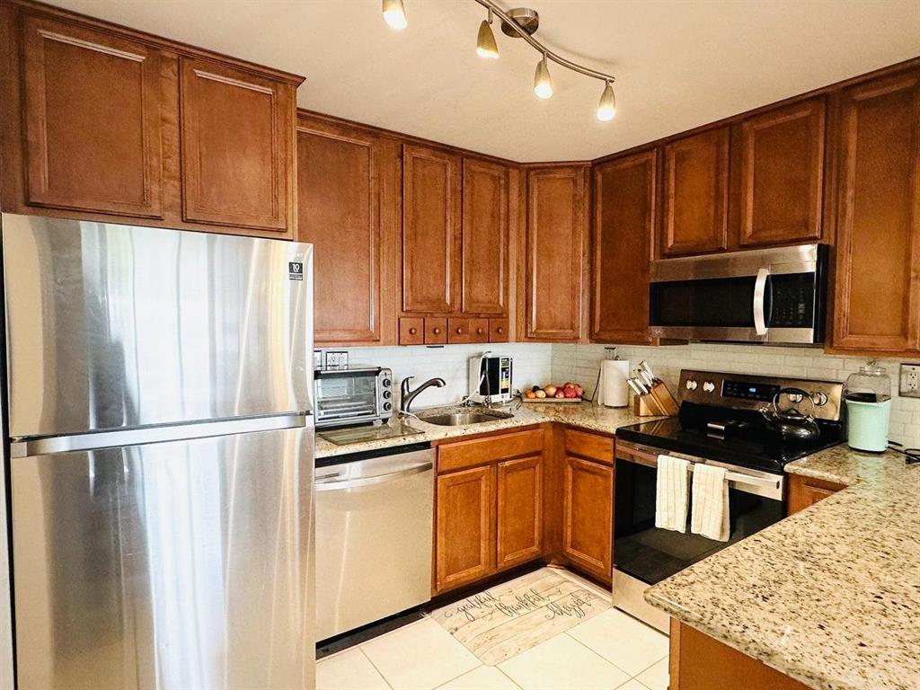 9300 Southwest 8th Street, Unit 214 Boca Raton, FL 33428 - Photo 11 of 32 a kitchen with stainless steel appliances granite countertop a sink stove and refrigerator