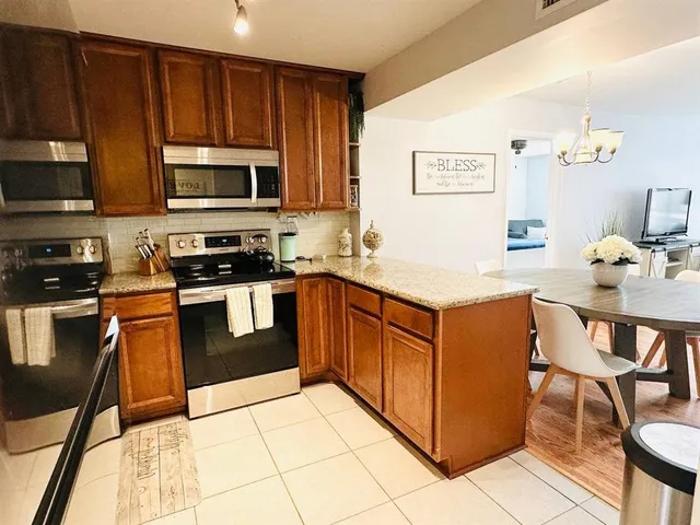 a kitchen with stainless steel appliances granite countertop a stove top oven a sink dishwasher and a refrigerator