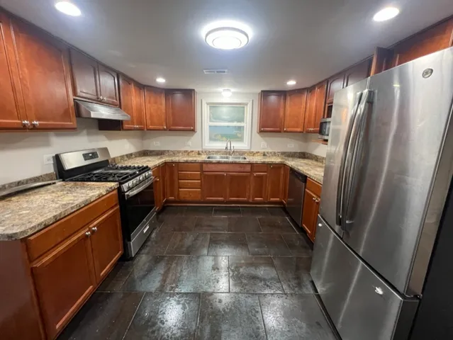 a kitchen with stainless steel appliances granite countertop hardwood a sink a stove and refrigerator