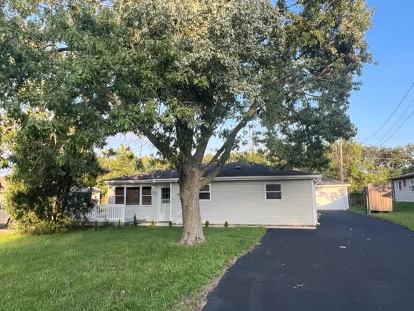 a front view of a house with a garden and trees