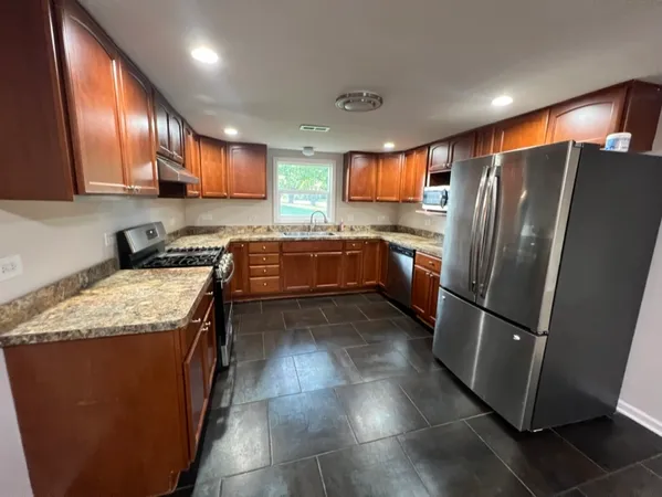 a kitchen with stainless steel appliances granite countertop a refrigerator a stove a sink and a microwave