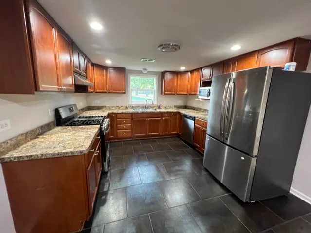 a kitchen with stainless steel appliances granite countertop a refrigerator a stove a sink and a microwave