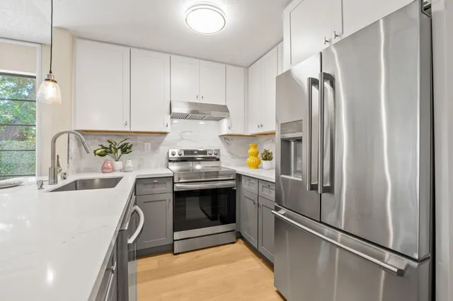a kitchen with stainless steel appliances a refrigerator sink and white cabinets