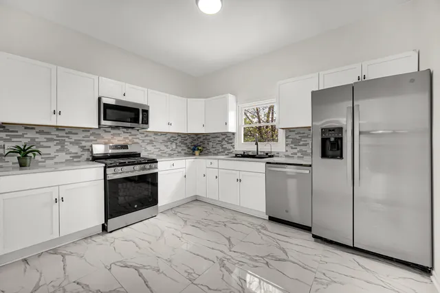 a kitchen with granite countertop white cabinets and stainless steel appliances