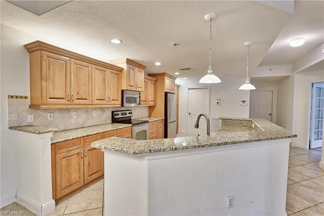 a kitchen with stainless steel appliances granite countertop a sink a stove and a refrigerator