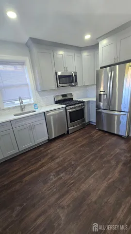 a kitchen with granite countertop a refrigerator and a stove top oven