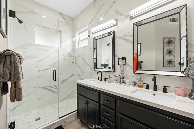 a bathroom with a double vanity sink a mirror and shower
