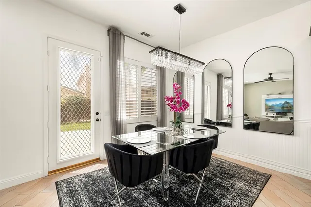 a dining room with wooden floor a chandelier a wooden table and chairs