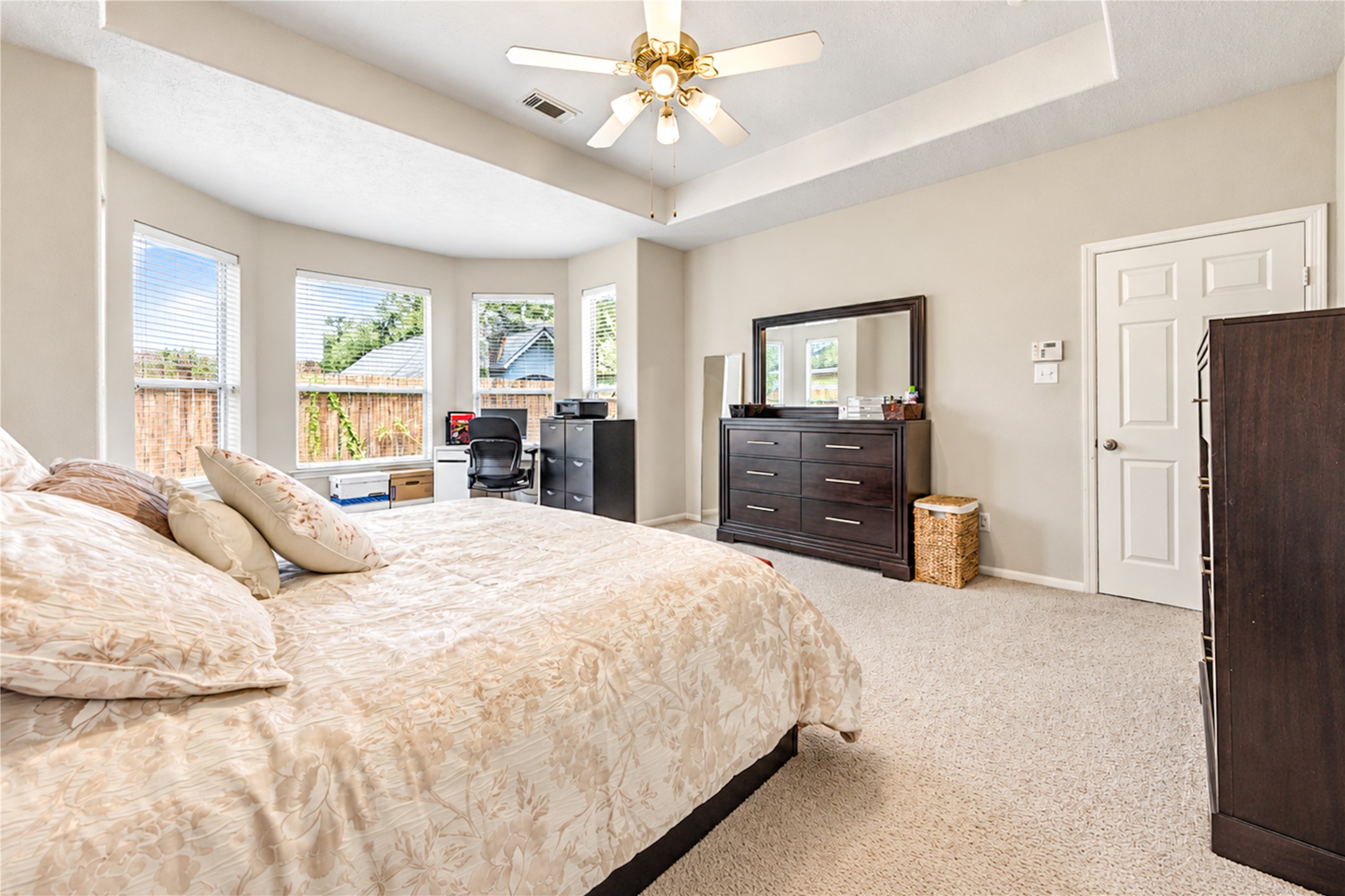 12806 Ridge Bank Lane Houston, TX 77041 - Photo 20 of 44 Spacious master bedroom featuring large windows for natural light, a cozy carpeted floor, and a ceiling fan for comfort.