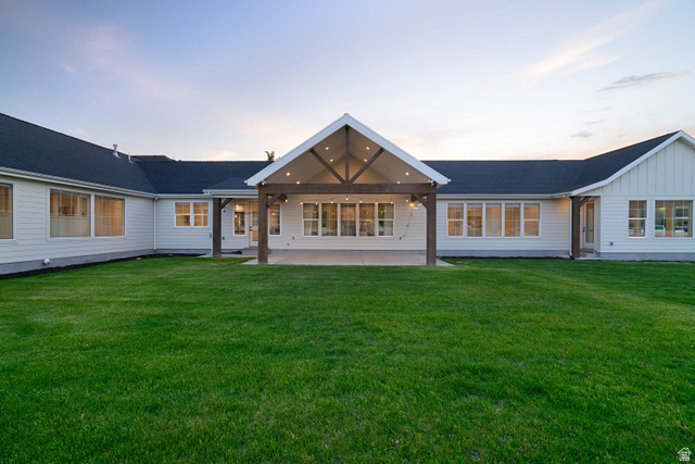 1952 South Comanche Circle Farmington, UT 84025 - Photo 48 of 52 Back of house featuring a patio area, board and batten siding, and a lawn