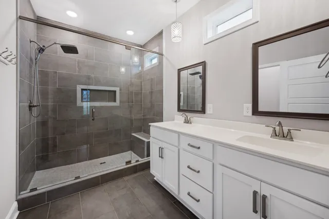 a spacious bathroom with double sink shower and a mirror