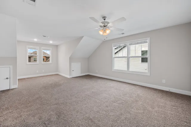 an empty room with windows and chandelier fan