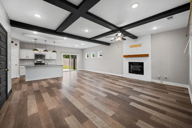 a large white kitchen with wooden floors and a fireplace