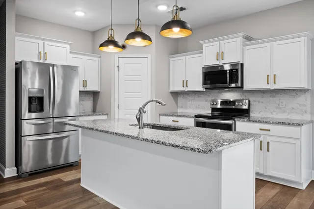 a kitchen with stainless steel appliances granite countertop a sink a stove a refrigerator a microwave oven with cabinets and wooden floor