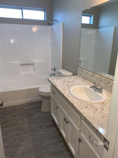 316 West Felspar Avenue Ridgecrest, CA 93555 - Photo 6 of 16 a bathroom with a granite countertop sink a toilet and a mirror