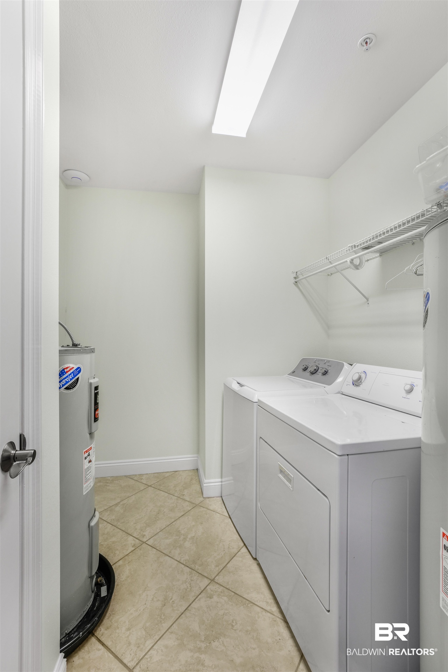 28250 Canal Road, Unit 106 Orange Beach, AL 36561 - Photo 31 of 50 Laundry area with light tile patterned floors, washing machine and clothes dryer, and water heater
