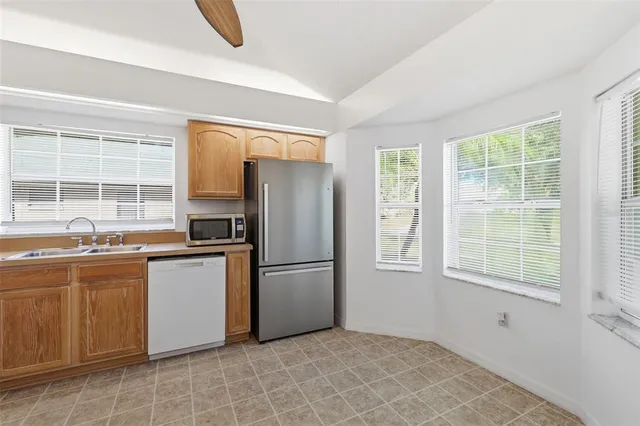 a kitchen with granite countertop a refrigerator a stove a sink dishwasher and wooden cabinets