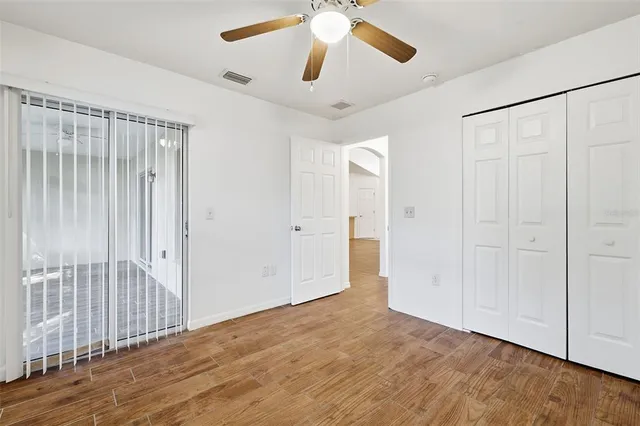 an empty room with wooden floor closet and windows