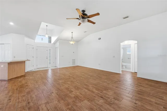 an empty room with wooden floor and ceiling fan